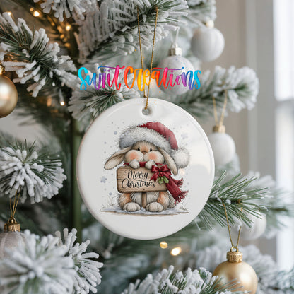 Christmas rabbit holding a Merry Christmas sign ceramic Christmas ornament hanging on a frosted Christmas tree