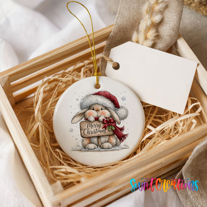 Christmas rabbit holding a Merry Christmas sign ceramic Christmas ornament displayed in a wooden gift crate