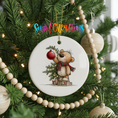 teddy bear holding a red ornament beside a Christmas tree ceramic Christmas ornament hanging on a green Christmas tree