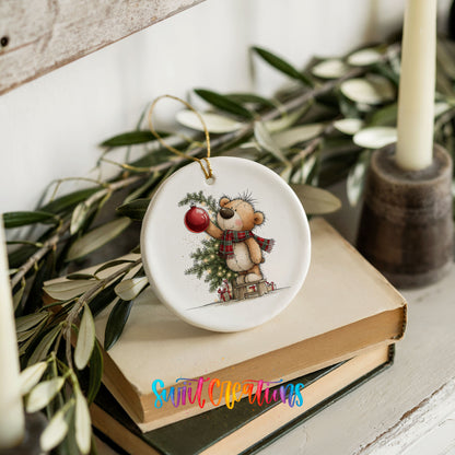 teddy bear holding a red ornament beside a Christmas tree ceramic Christmas ornament styled on stacked books with greenery