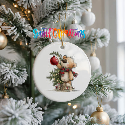 teddy bear holding a red ornament beside a Christmas tree ceramic Christmas ornament hanging on a frosted Christmas tree