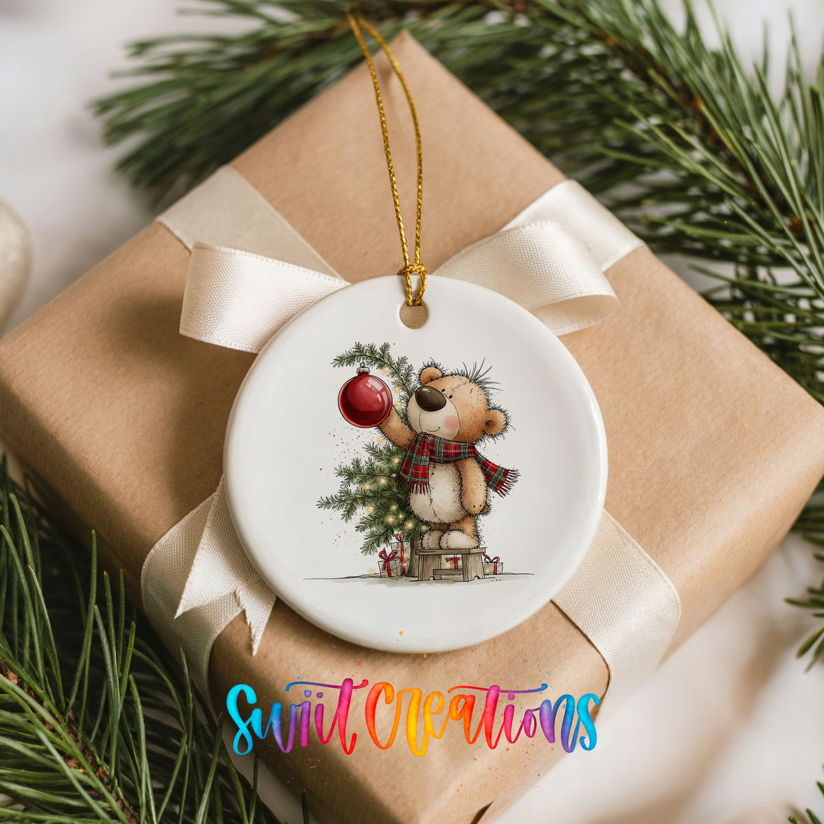 teddy bear holding a red ornament beside a Christmas tree ceramic Christmas ornament displayed on a wrapped Christmas gift