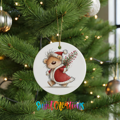teddy bear carrying a red Christmas sack with winter greenery ceramic Christmas ornament hanging on a lit Christmas tree