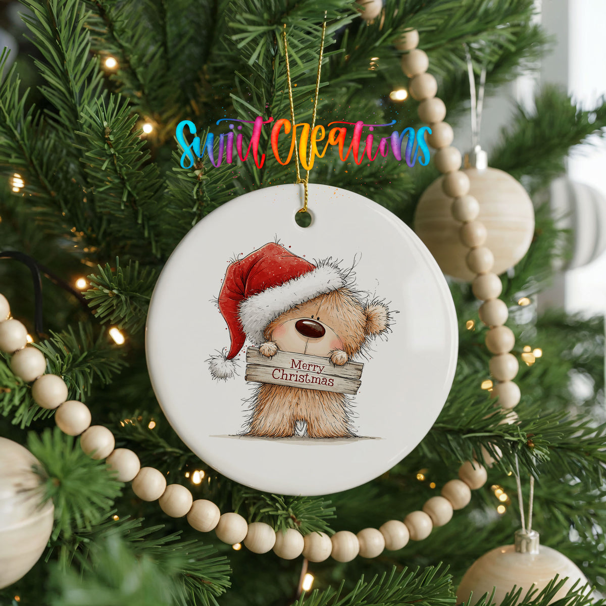 teddy bear in a Santa hat holding a Merry Christmas sign ceramic Christmas ornament hanging on a green Christmas tree