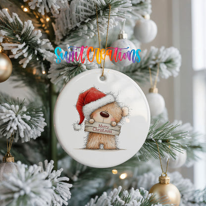 teddy bear in a Santa hat holding a Merry Christmas sign ceramic Christmas ornament hanging on a frosted Christmas tree