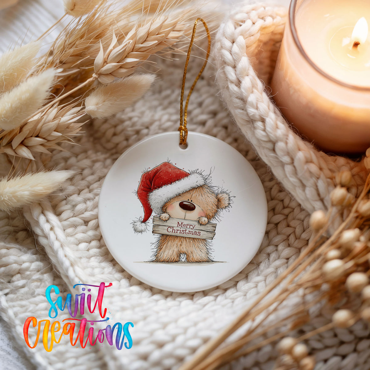 teddy bear in a Santa hat holding a Merry Christmas sign ceramic Christmas ornament styled on a cozy knit blanket