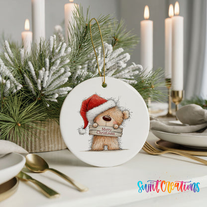 teddy bear in a Santa hat holding a Merry Christmas sign ceramic Christmas ornament shown in a holiday table setting