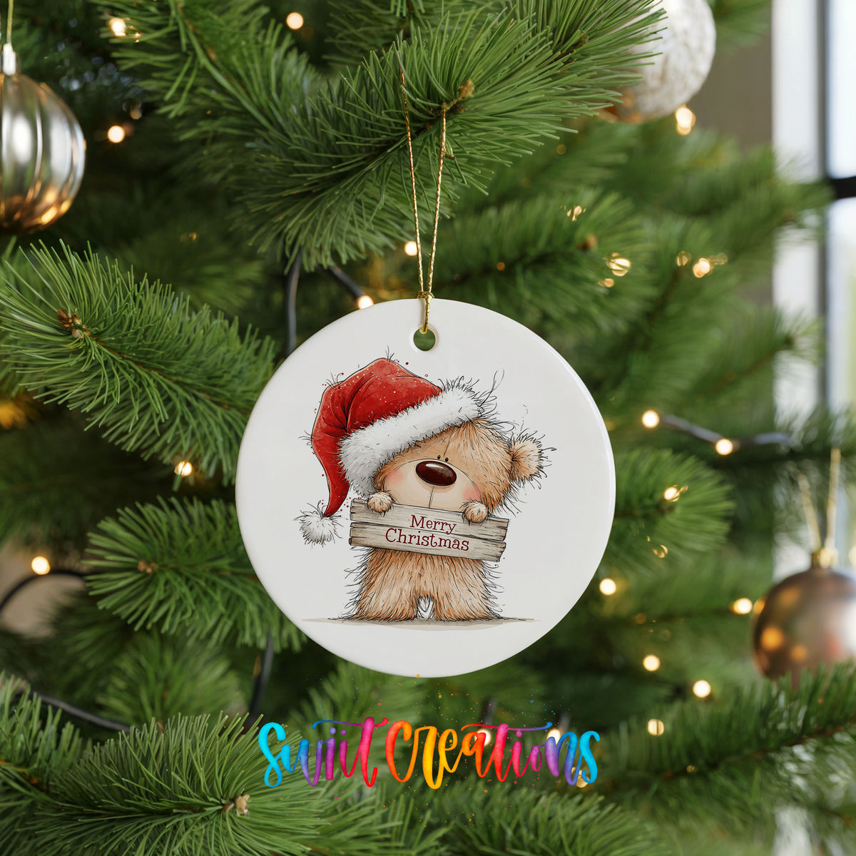 teddy bear in a Santa hat holding a Merry Christmas sign ceramic Christmas ornament hanging on a lit Christmas tree
