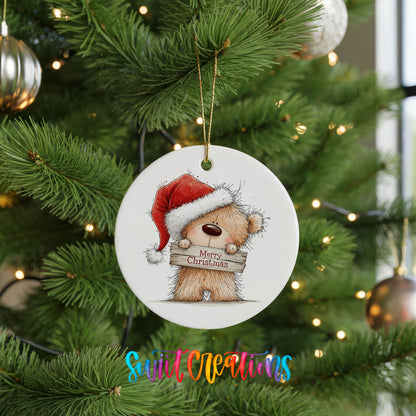 teddy bear in a Santa hat holding a Merry Christmas sign ceramic Christmas ornament hanging on a lit Christmas tree