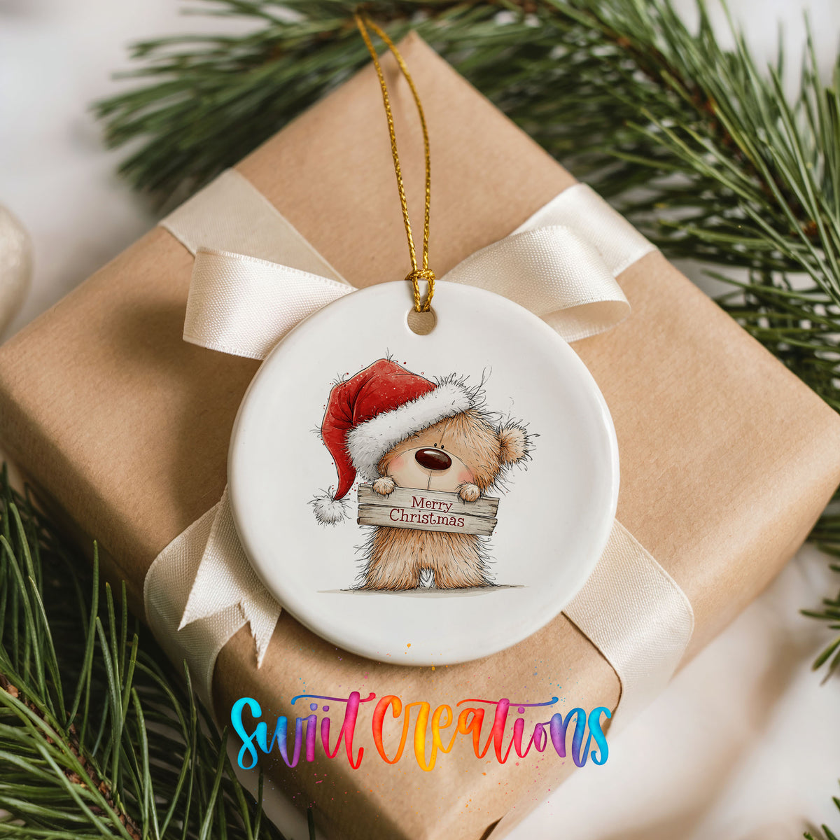 teddy bear in a Santa hat holding a Merry Christmas sign ceramic Christmas ornament displayed on a wrapped Christmas gift
