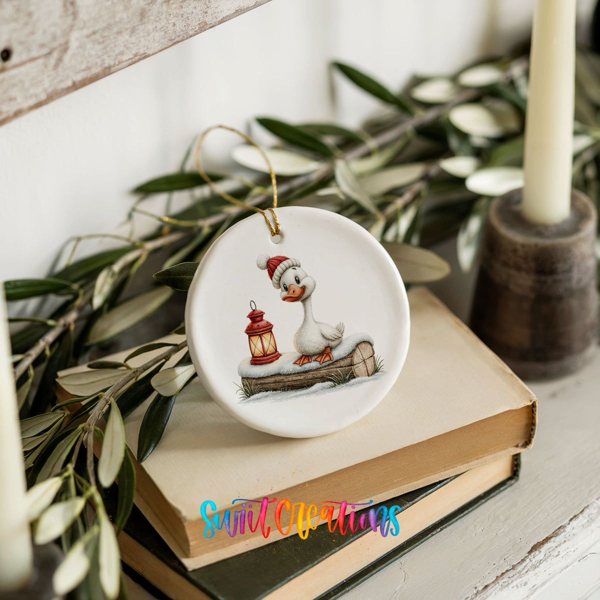 Christmas goose standing beside a red lantern ceramic Christmas ornament styled on stacked books with greenery