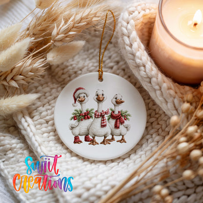three Christmas geese wearing holiday wreaths ceramic Christmas ornament styled on a cozy knit blanket