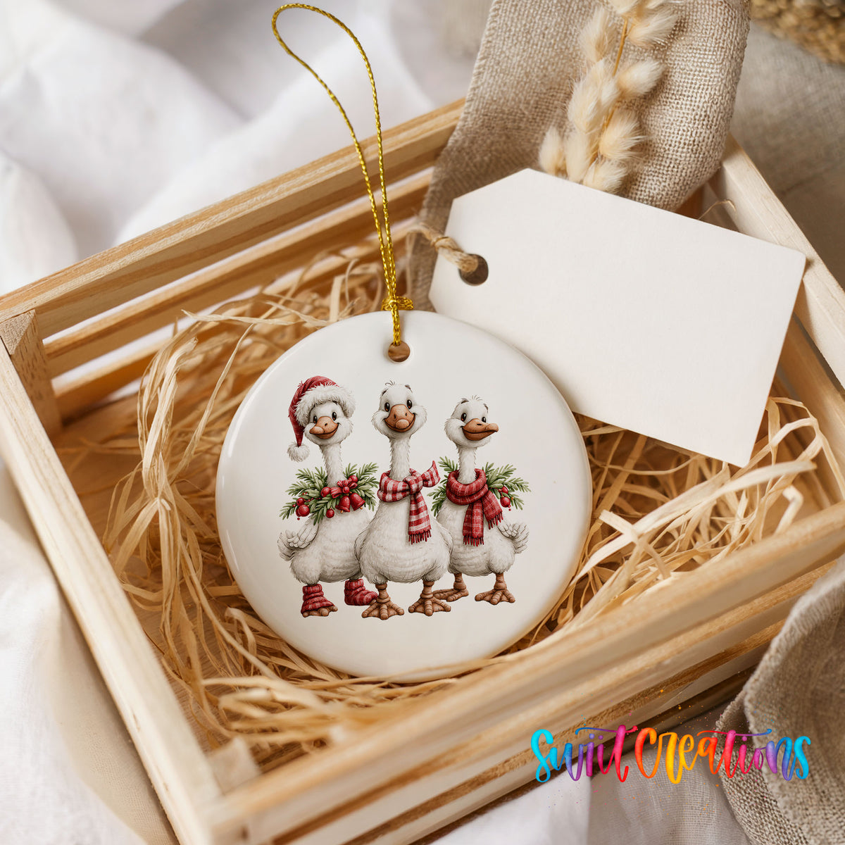 three Christmas geese wearing holiday wreaths ceramic Christmas ornament displayed in a wooden gift crate
