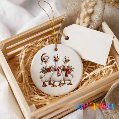 three Christmas geese wearing holiday wreaths ceramic Christmas ornament displayed in a wooden gift crate