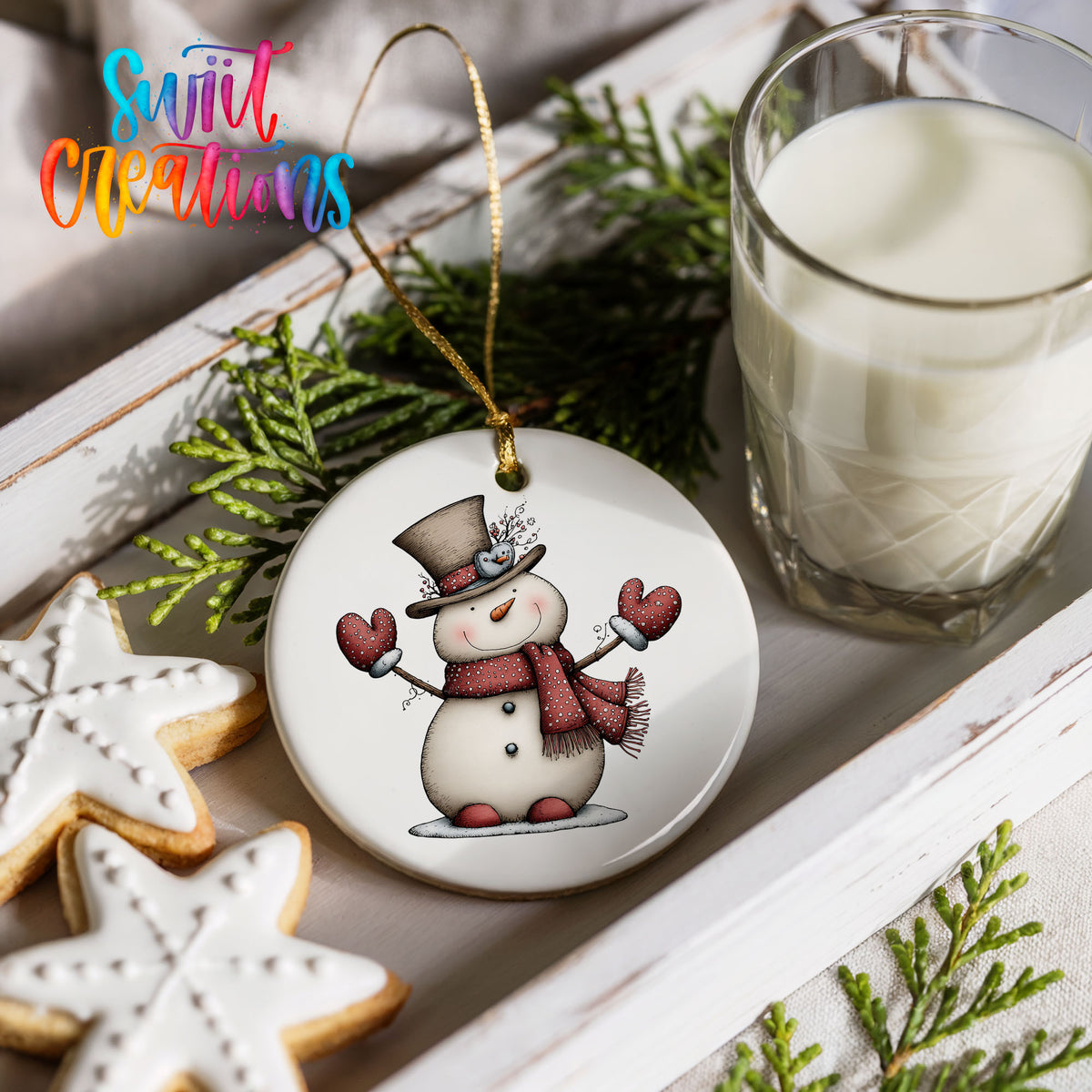 snowman in a top hat with red heart mittens ceramic Christmas ornament styled with holiday cookies and a candle