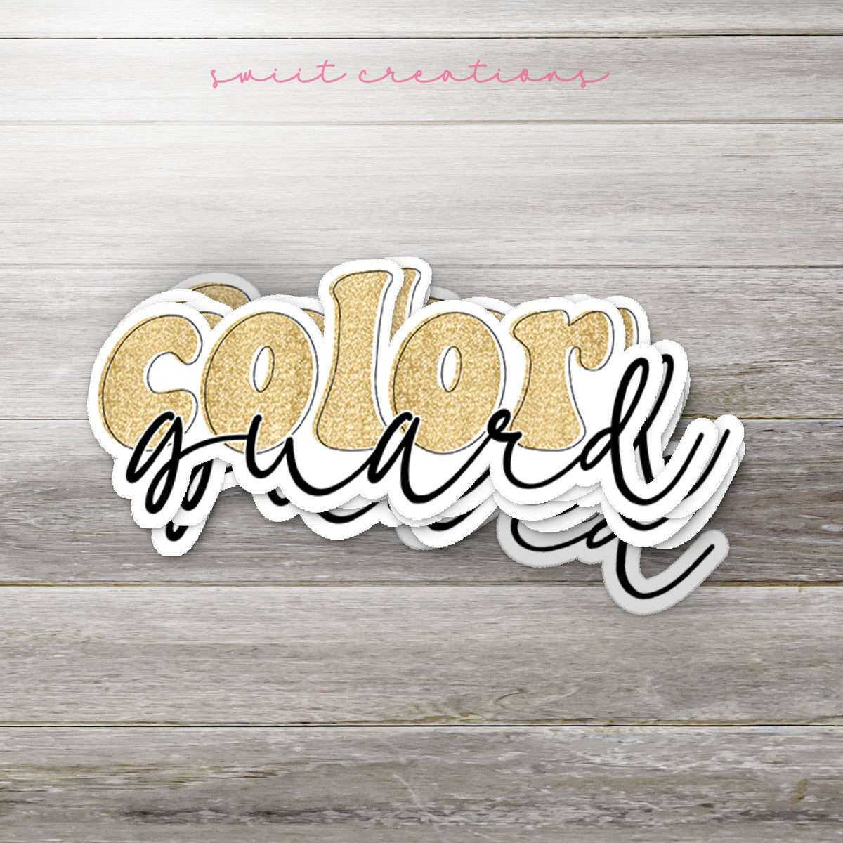 Stack of Gold Glitter Color Guard glossy stickers on a gray wood table