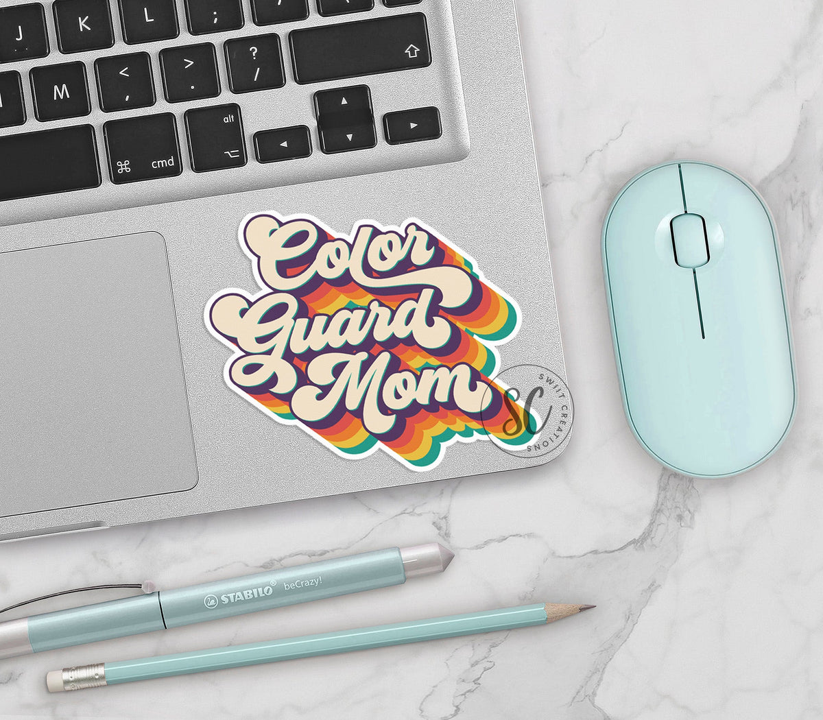 Retro Color Guard Mom vinyl sticker on a silver laptop next to a mint mouse and pens