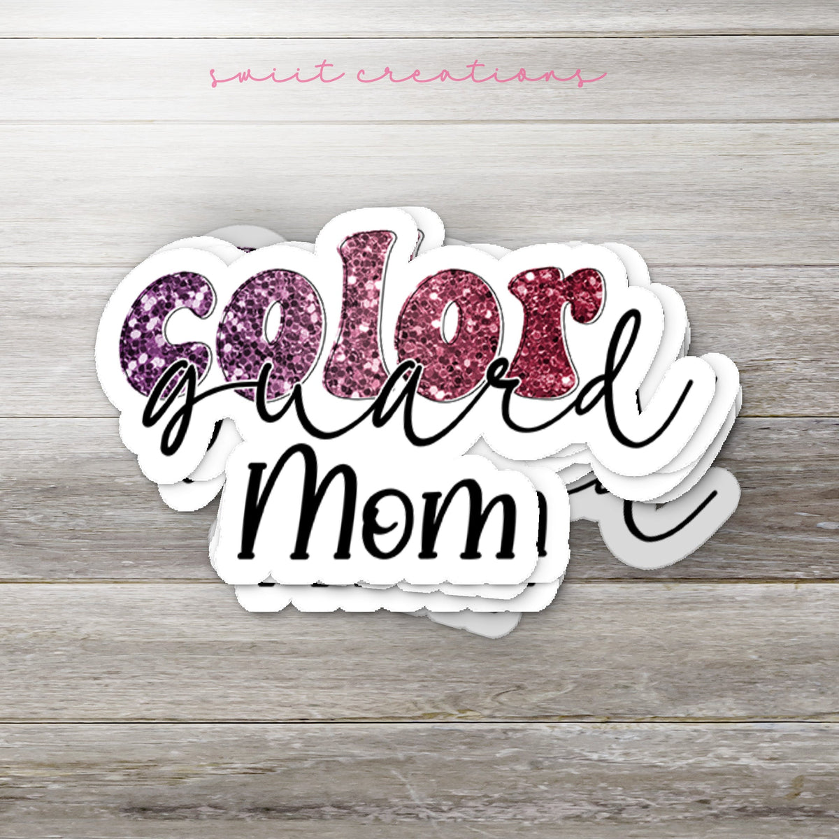 Stack of Maroon Glitter Color Guard Mom glossy stickers on a gray wood table