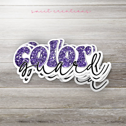 Stack of Purple Glitter Color Guard glossy stickers on a gray wood table