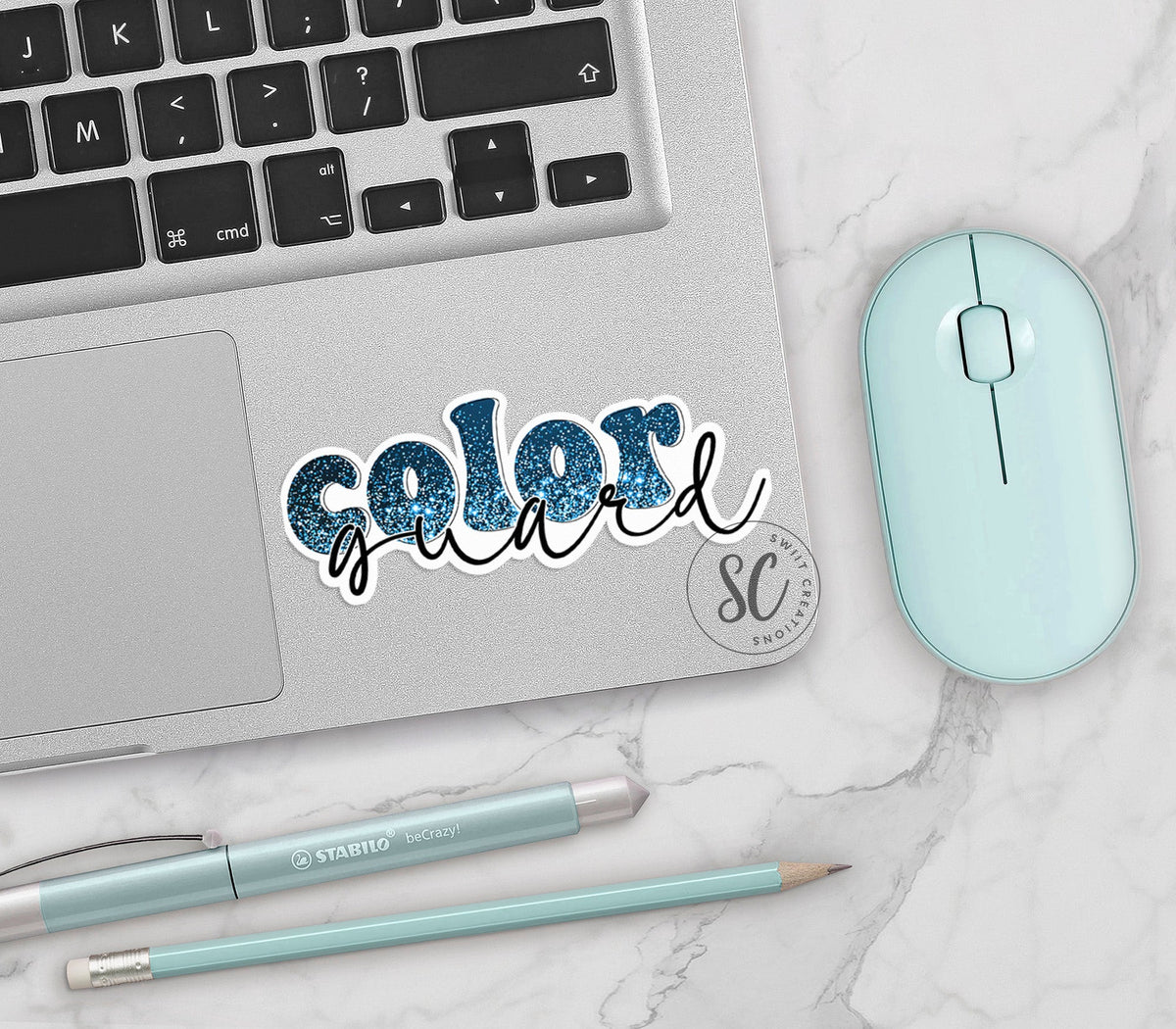 Blue Glitter Color Guard vinyl sticker on a silver laptop next to a mint mouse and pens