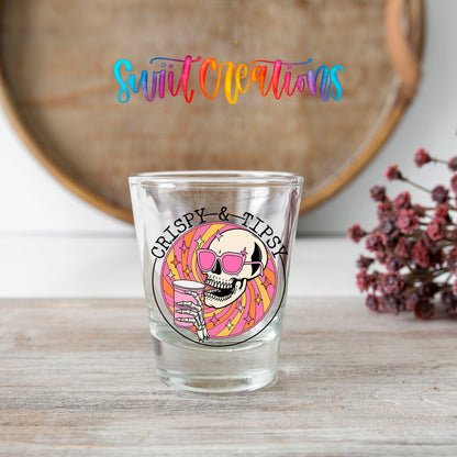 Crispy and Tipsy shot glass transfer on a clear glass beside a wooden barrel and dried flowers