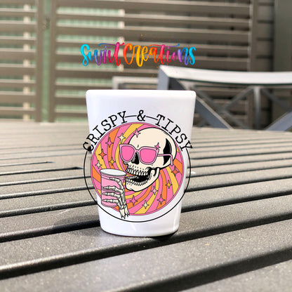 Crispy and Tipsy UV DTF transfer on a white shot glass on an outdoor patio table