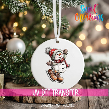 Ice Skating Snowman ornament UV DTF transfer on an ornament resting on a wood slice beside a Christmas tree
