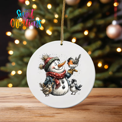 Snowman with Birds ornament UV DTF transfer on an ornament on a wooden table with tree lights behind it