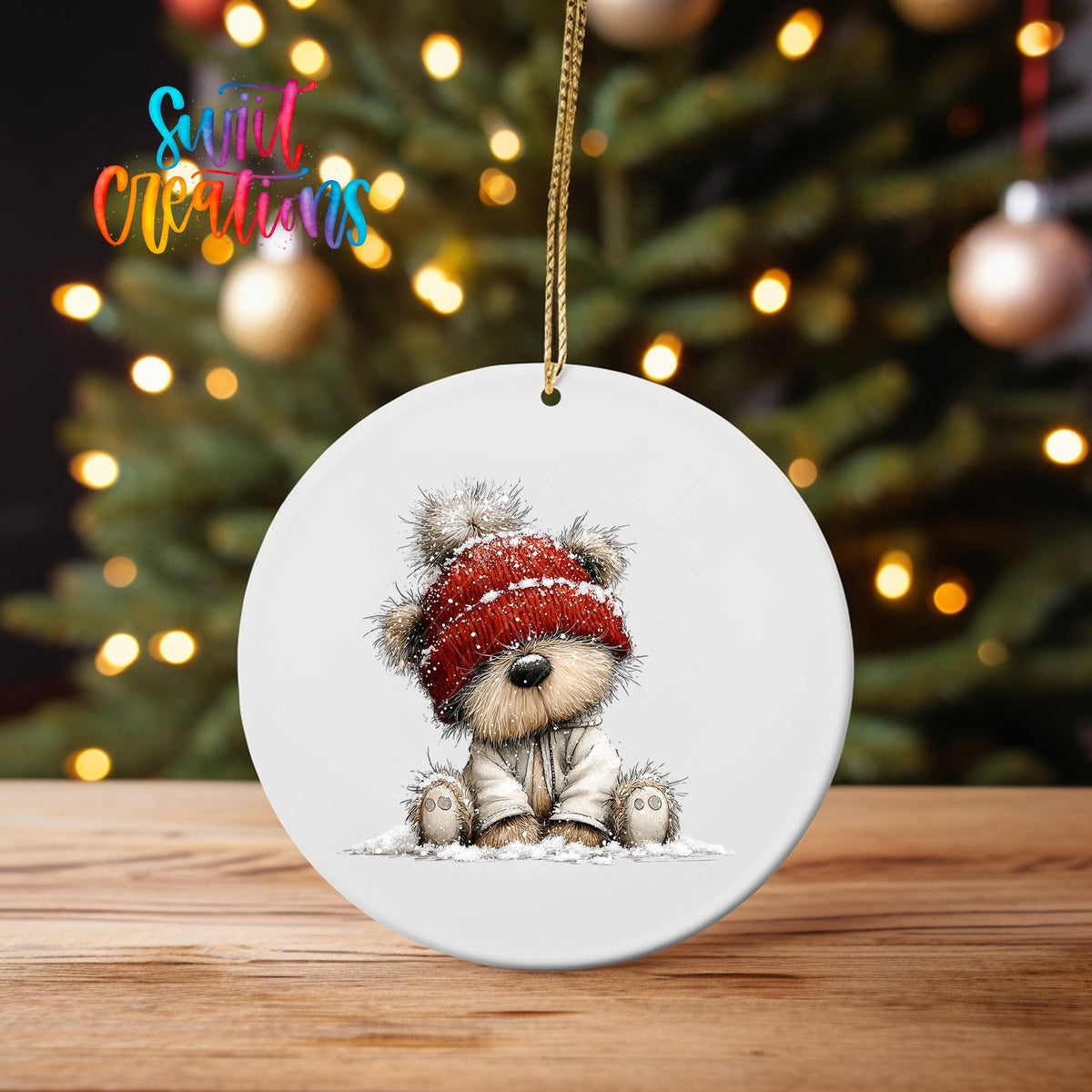 Teddy Bear in Red Beanie ornament UV DTF transfer on an ornament on a wooden table with tree lights behind it