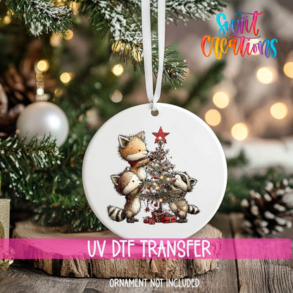 Woodland Friends Decorating a Tree ornament UV DTF transfer on an ornament resting on a wood slice beside a Christmas tree
