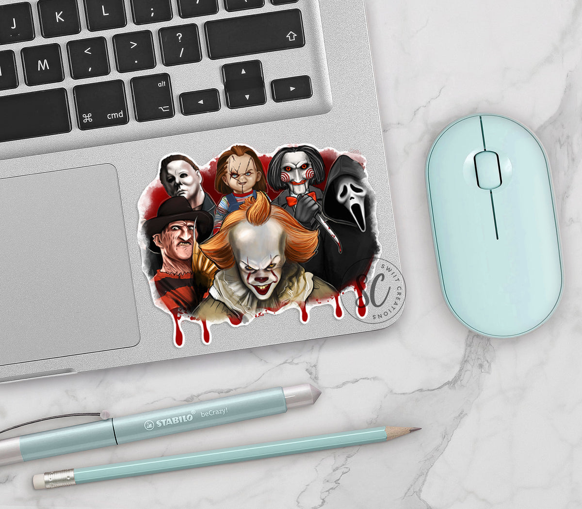Horror Movie Villains vinyl sticker on a silver laptop next to a mint mouse and pens