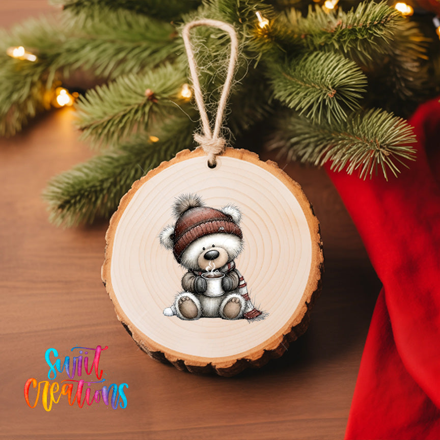 A wooden ornament featuring a teddy bear wearing a hat and scarf, hanging on a Christmas tree.