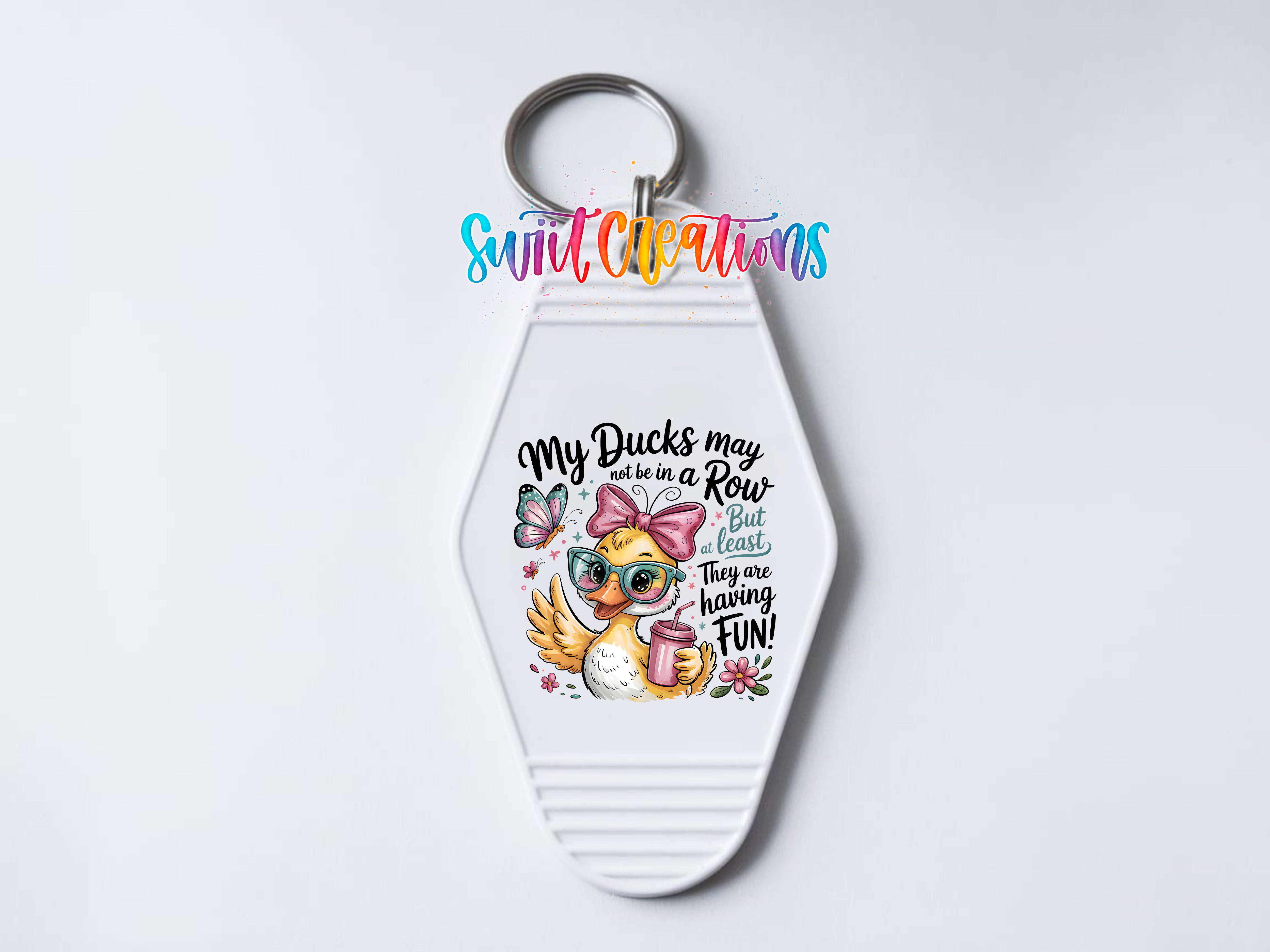 A keychain with a cartoon duck and text that says "My ducks may not be in a row but they are still here. They are still here because they are having fun!"