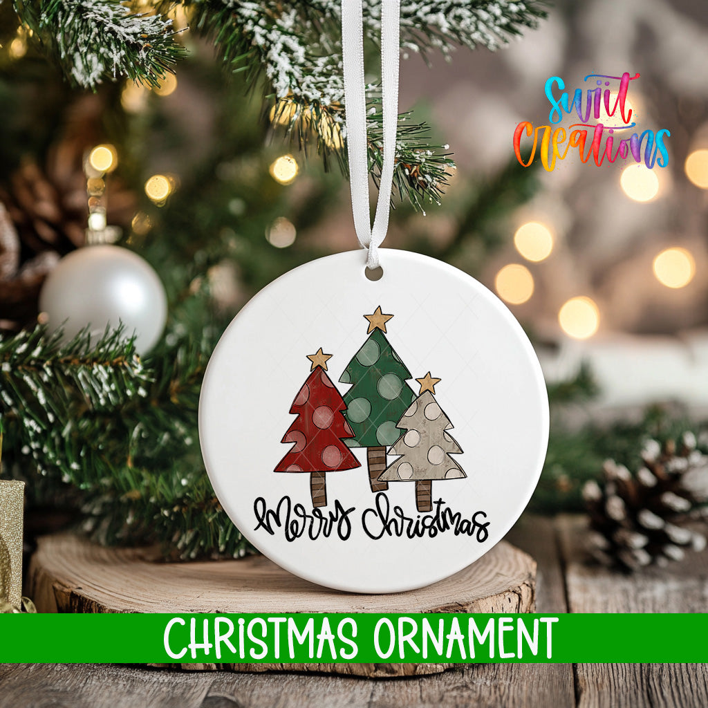 A white Christmas ornament with a design of three trees and the text "Merry Christmas" hanging from a string.
