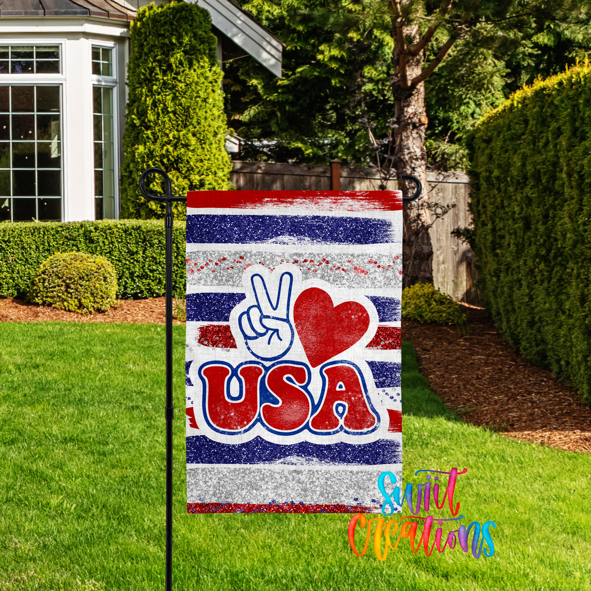 A patriotic flag with the word "USA" and a peace sign is displayed in a grassy yard, with a house and trees in the background.