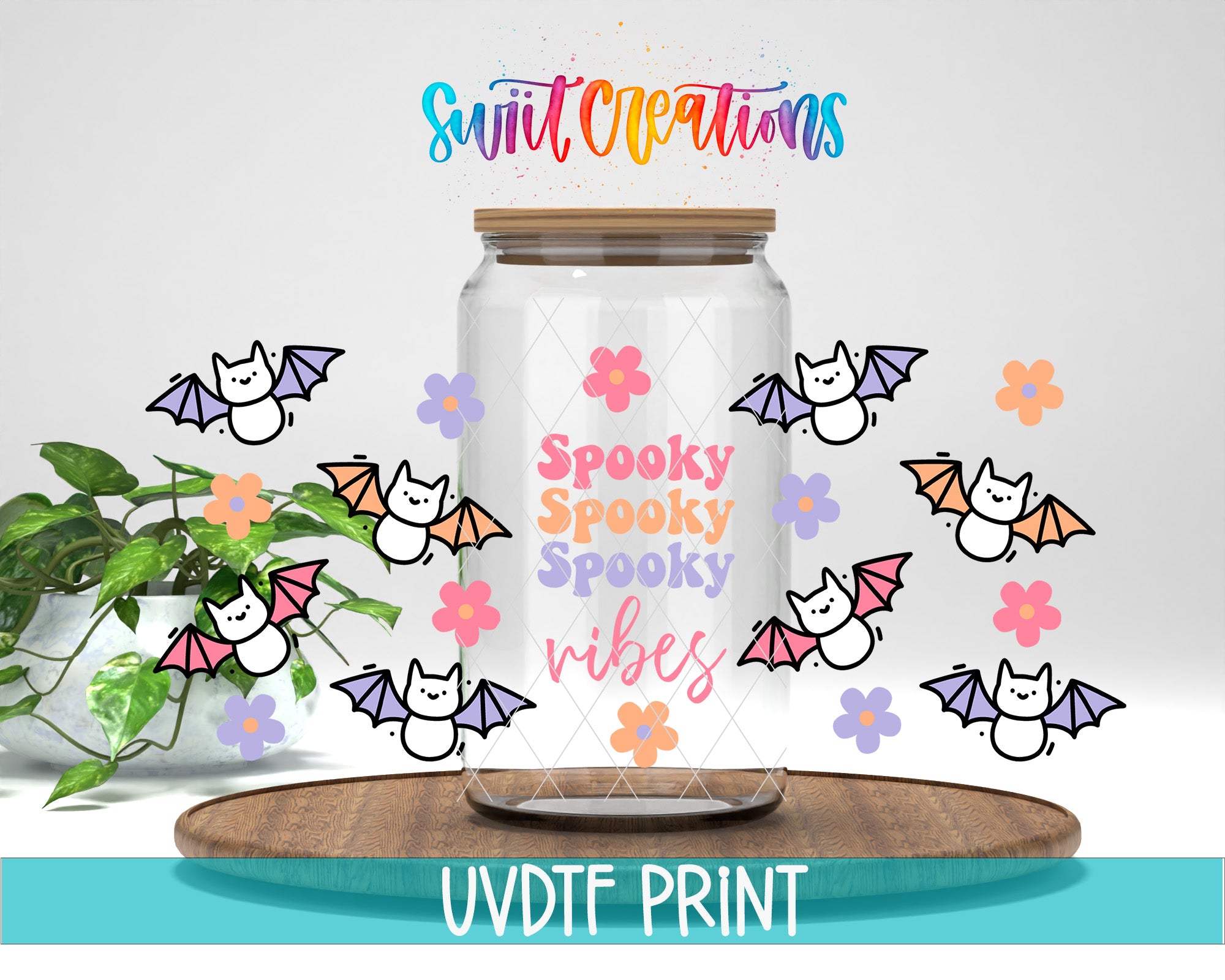 a glass jar with a lid, decorated with bats and flowers, and the text "Spooky Spooky Vibes" written on it. The jar is placed on a wooden surface, and there is a plant in the background.