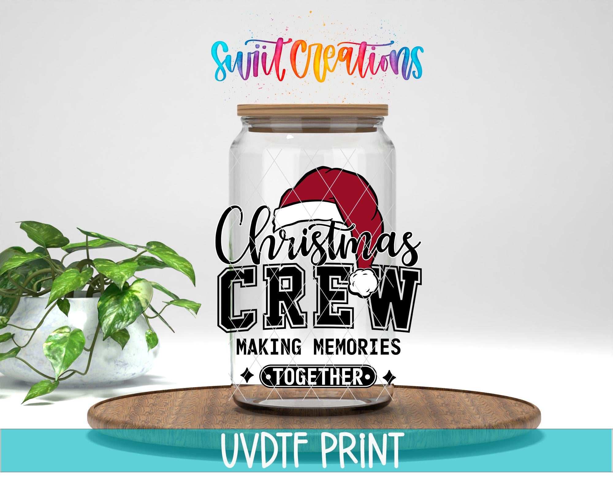 A glass jar with a Christmas-themed design, including a Santa hat and the text "Christmas Crew Making memories together". The jar is placed on a wooden tray, and there is a potted plant in the background.