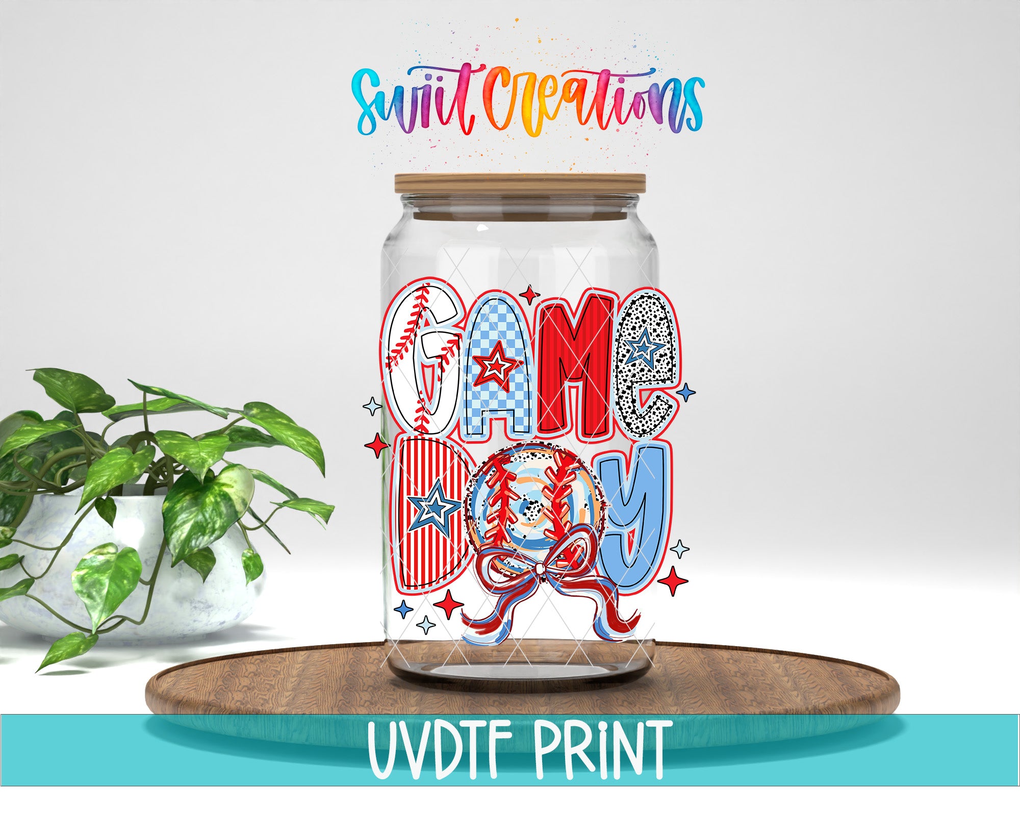 a glass jar with a colorful design, including the words "GAME DAY" and various sports-related elements such as a baseball, a football, and a baseball bat. The jar is placed on a wooden surface, and there is a potted plant in the background.