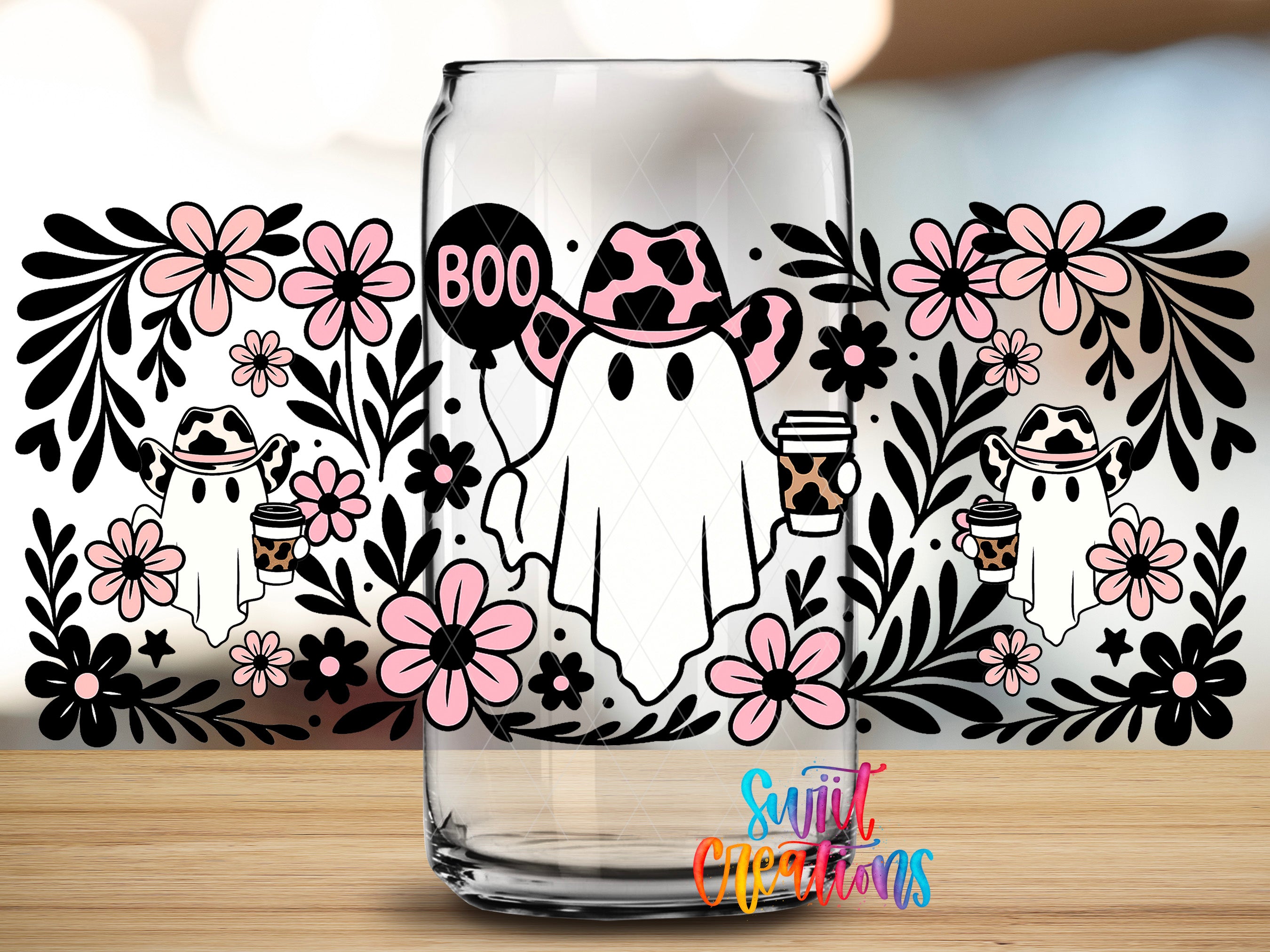A glass mug with a Halloween-themed design featuring a ghost wearing a cowboy hat and holding a coffee cup, surrounded by pink flowers and black silhouettes of ghostly figures.