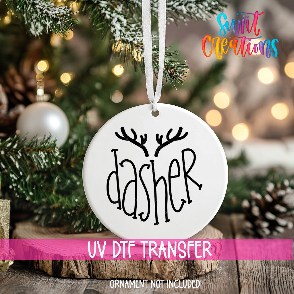 A white ornament with the word "dasher" printed on it, hanging from a Christmas tree.