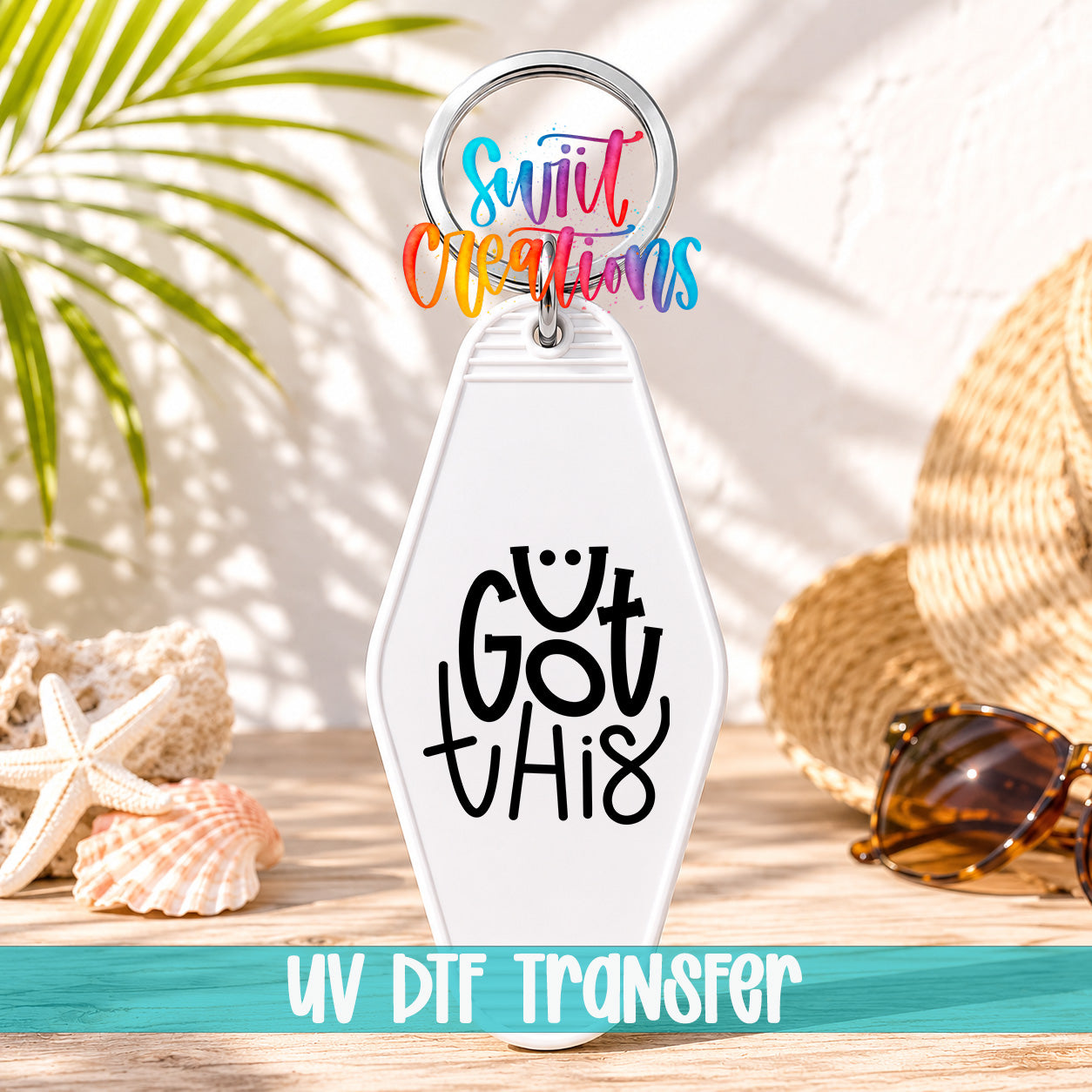 A keychain with the text "Got this" printed on it, along with a colorful ring and sunglasses on a wooden surface.