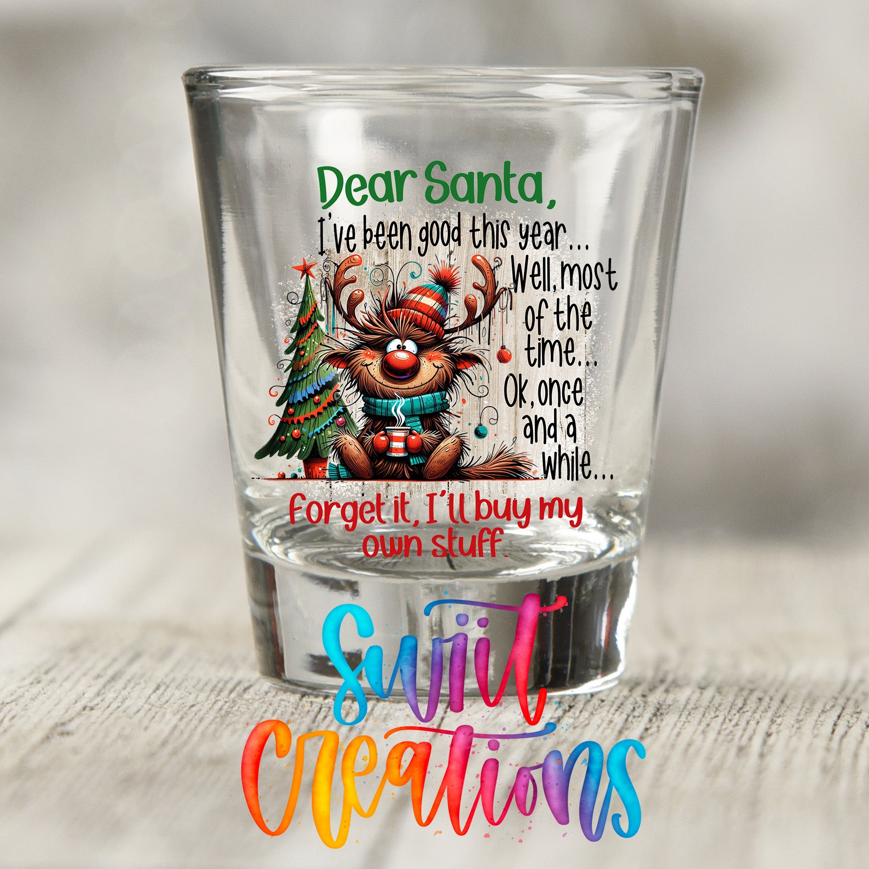 A glass shot glass with a Christmas-themed design featuring a reindeer and a message from Santa.