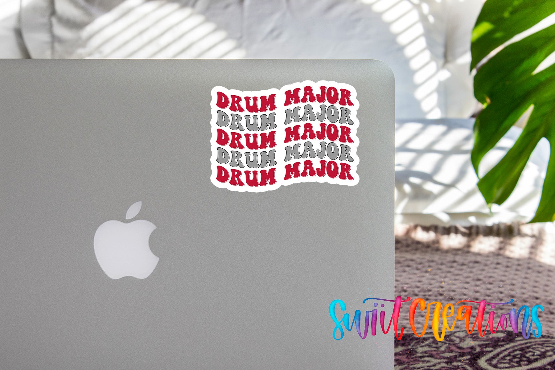 a sticker with the word "DRUM" repeated in a decorative pattern on the back of a silver laptop.