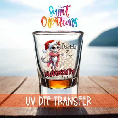 Definitely on the Naughty List Christmas shot glass UV DTF transfer on a filled shot glass on a dock by the water
