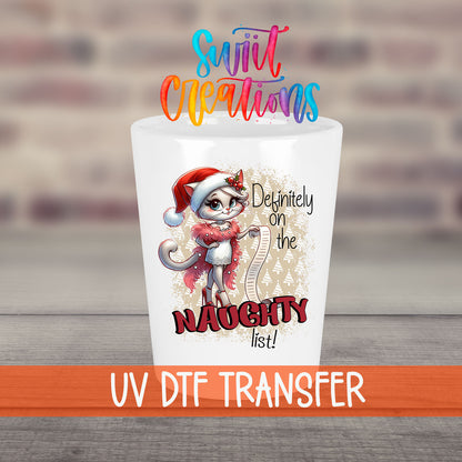 Definitely on the Naughty List Christmas UV DTF transfer on a white shot glass in front of a brick wall
