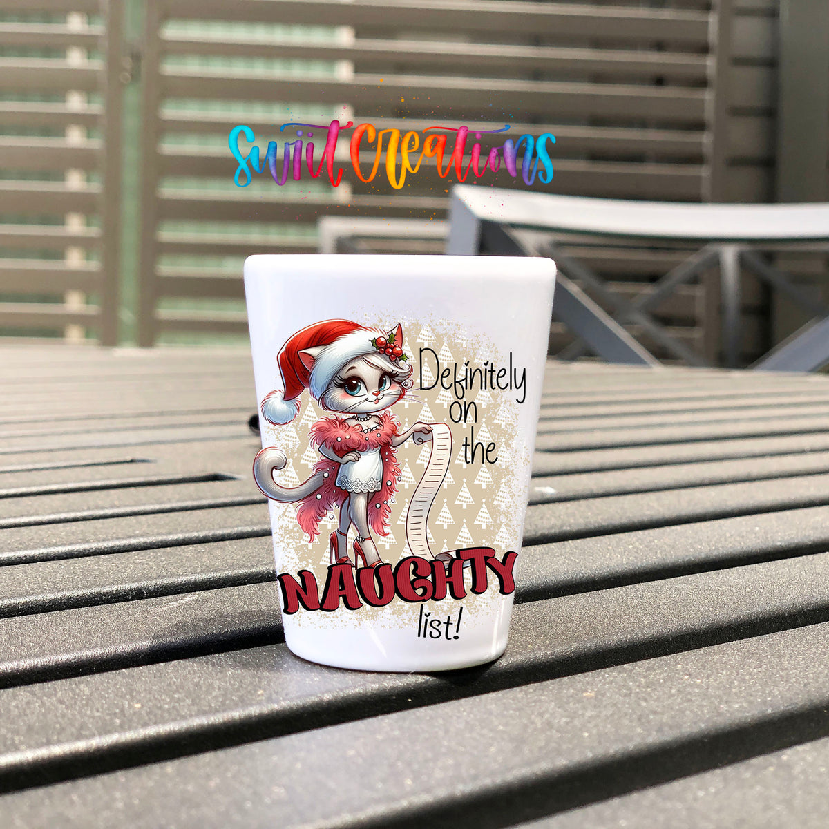 Definitely on the Naughty List Christmas UV DTF transfer on a white shot glass on an outdoor patio table