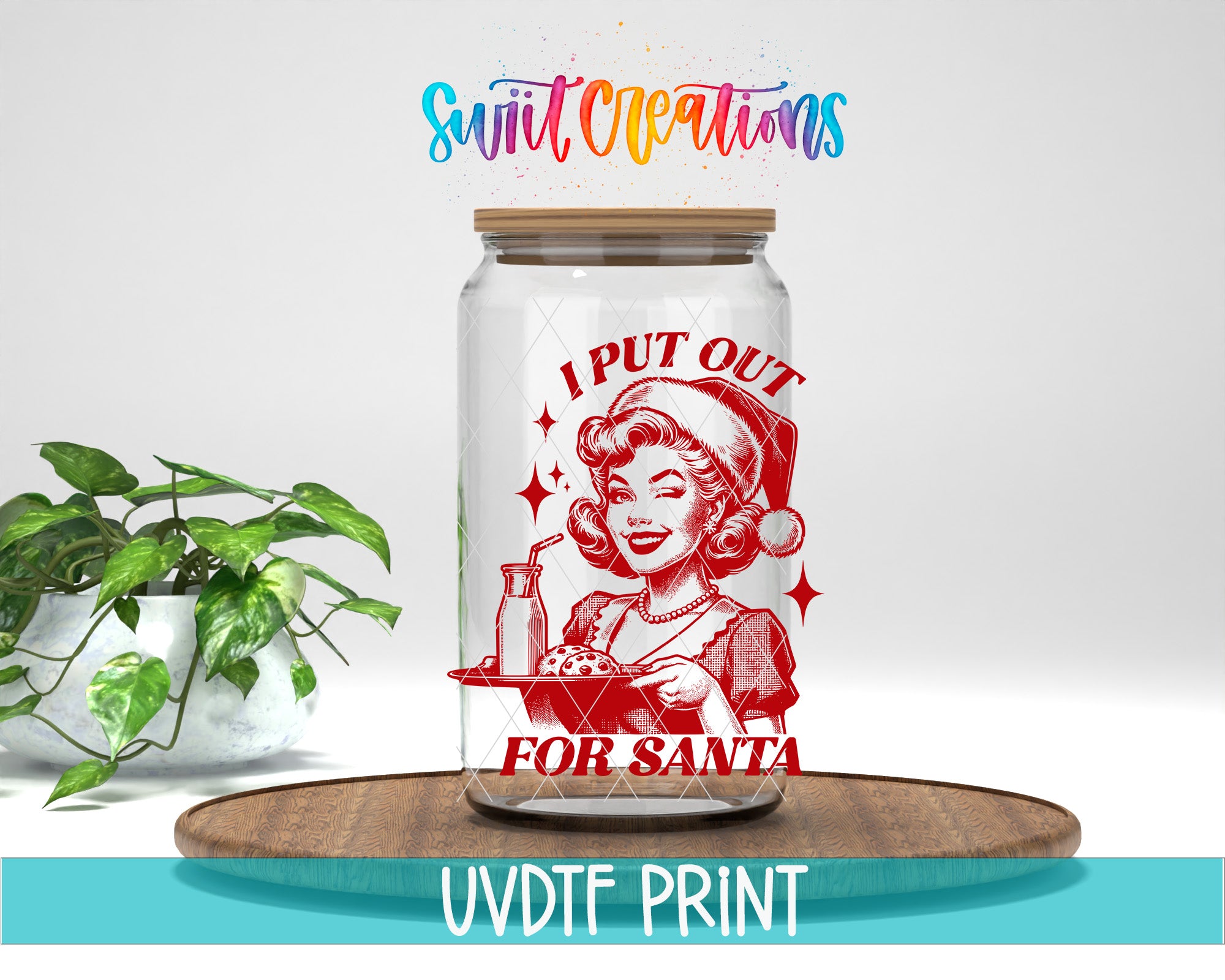 A glass jar with a red and white illustration of a woman in a Santa hat, along with the text "I PUT OUT FOR SANTA" and "Swift Creations" written above it. The jar is placed on a wooden surface, and there is a potted plant in the background.