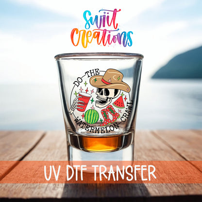 Do The Watermelon Crawl shot glass UV DTF transfer on a filled shot glass on a dock by the water