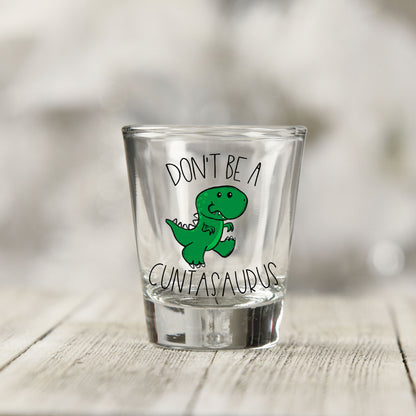 Close-up of the Don't Be a Cuntasaurus UV DTF transfer on a clear shot glass