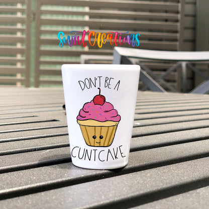 Don't Be a Cuntcake UV DTF transfer on a white shot glass on an outdoor patio table